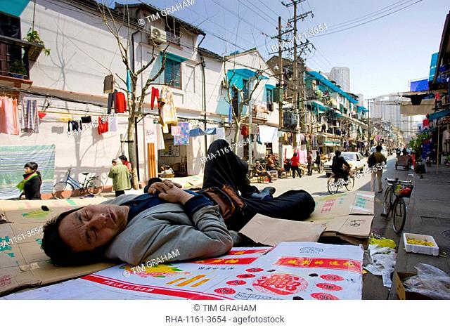 Man sleeps on cardboard in Zi Zhong Road, old Shanghai, China