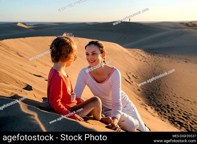 Happy mother and daughter relaxing in sand dunes, Gran Canaria, Spain