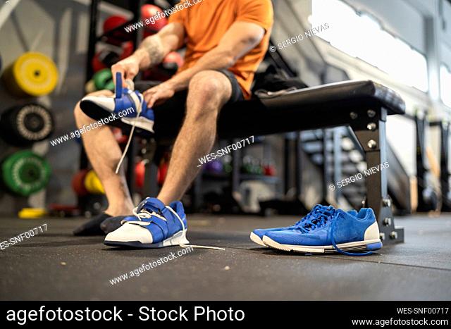Male athlete wearing sports shoe in gym