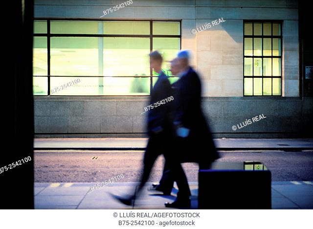 Three unrecognizable executives men in movement walking down the street in the City of London, England, UK
