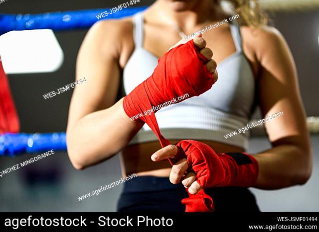 Close-up of young woman tying bandage around her hand in boxing club