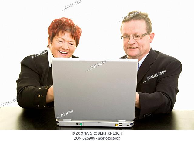 Ehepaar sitzt lachend vor einem Laptop
