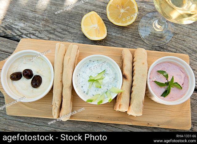 Meze at a Cypriot restaurant of Taramasalata, tzatziki, hummus, pitta bread, lemon and olives accompanied with white wine, Cyprus, Mediterranean, Europe
