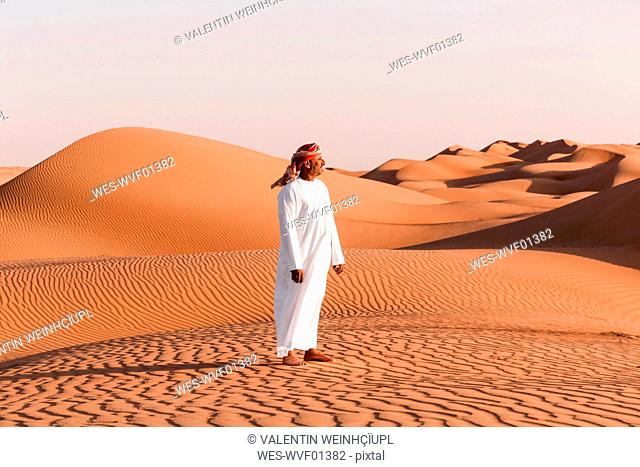 Bedouin in National dress standing in the desert, Wahiba Sands, Oman