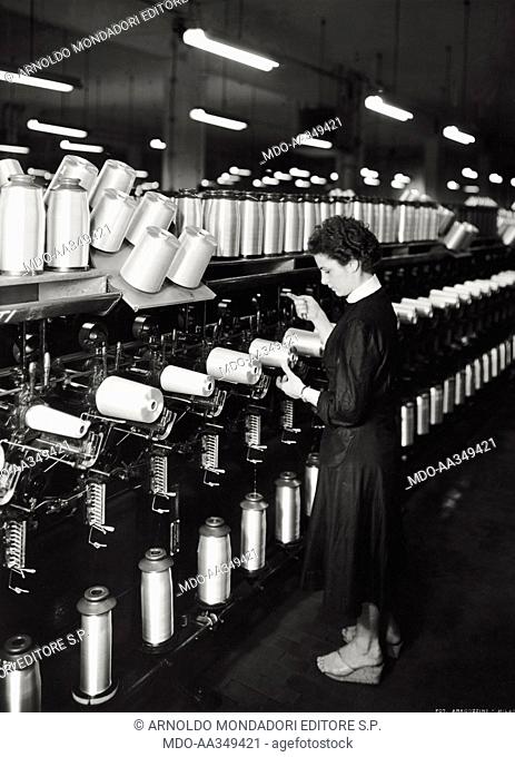 Woman at work. Italian worker controlling the machinery where textil fibers are collected at SNIA Viscosa textile company. Varedo, June 1953