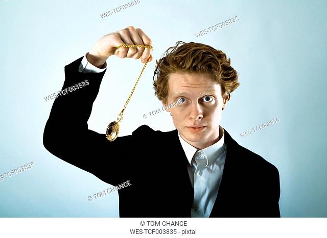 Portrait of young man swinging golden pocket watch