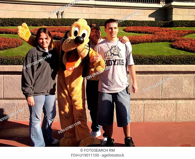 Orlando, FL, Florida, Walt Disney World Resort, Magic Kingdom Park, Pluto poses with teenagers for pictures (Editorial Use Only)