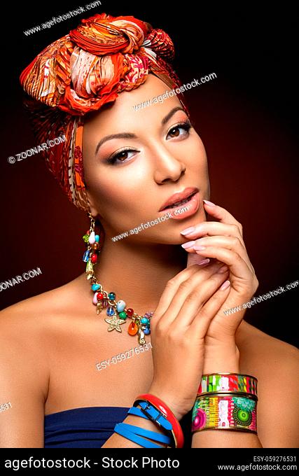 beautiful mulatto young woman with orange turban on head. beauty shot on dark background. copy space