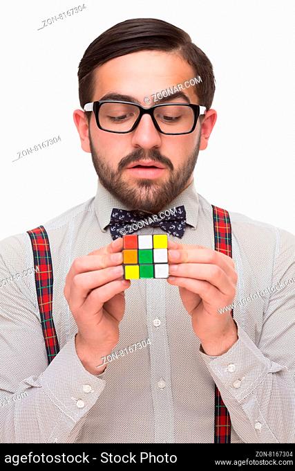 Close-up portrait of handsome boy nerd holding a rubik#39;s cube in front of him. Man looking at rubik#39;s cube isolated on white