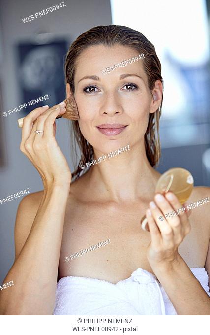 Portrait of blond woman applying makeup in the morning