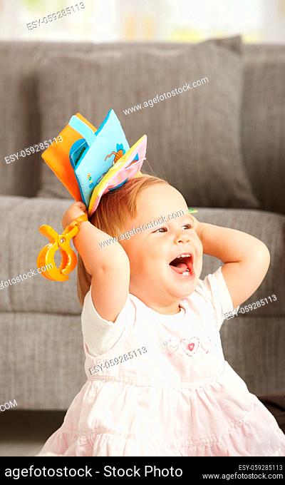Laughing babygirl with toy at home