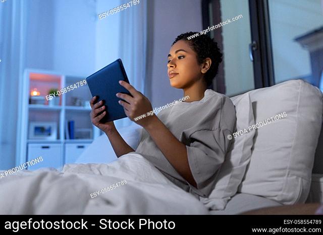 woman with tablet pc in bed at home at night