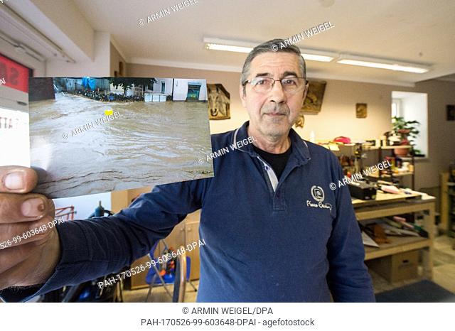Saddler Vasile Stratulat holds a picture of the flood in his hands while standing in his shop in Simbach am Inn, Germany, 18 May 2017