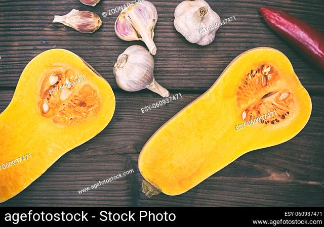 fresh pumpkin and garlic on a brown wooden background, top view