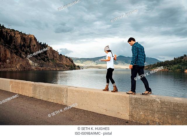 Couple walking along wall beside Dillon Reservoir, Silverthorne, Colorado, USA