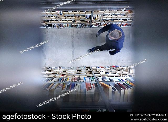 24 February 2022, Saxony, Leipzig: An employee walks ducch the warehouse of the online mail order company Momox, taken through a grating