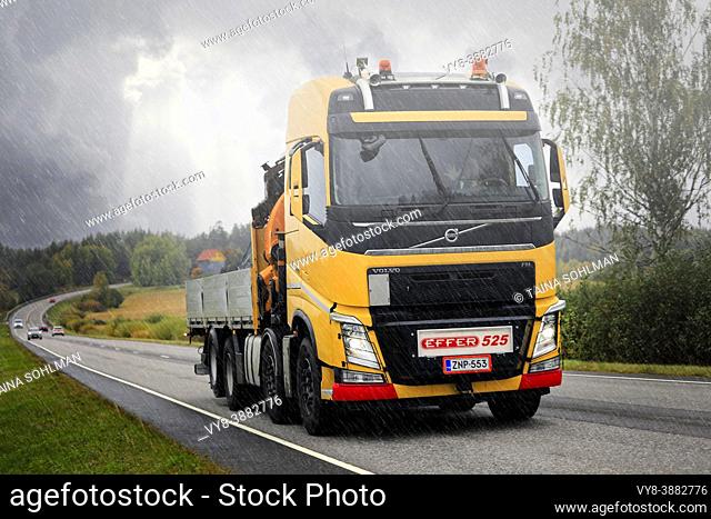 Yellow Volvo FH lorry for construction with Effer 525 truck mounted crane on the road on a rainy day in autumn. Salo, Finland. September 24, 2021