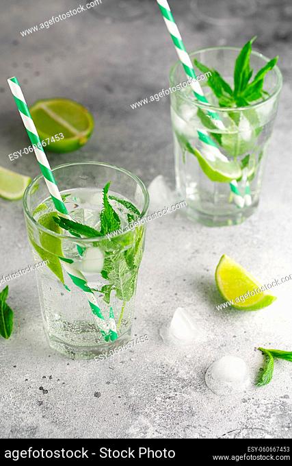 homemade lemonade with lime, mint in a glass on a gray concrete background. Healthy Fresh Mint Water with Lime and ice. Food photography