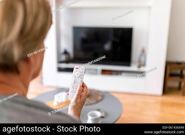 Senior woman with remote control watching television