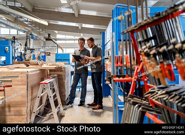 Two carpenters standing and talking in production hall