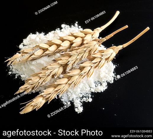 wheat ears with flour on black background