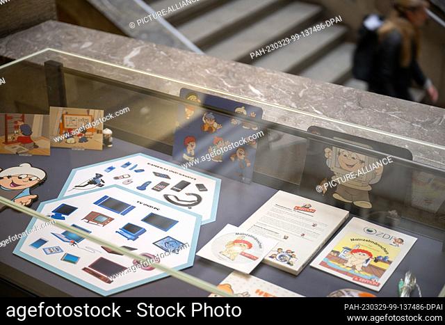 29 March 2023, Rhineland-Palatinate, Mainz: A woman walks past a display case with props for the Mainzelmännchen before the opening of the exhibition ""60 Years...