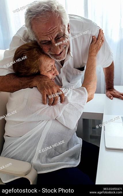 Happy senior man embracing mother at home
