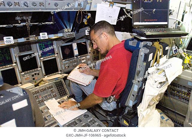 Astronaut Daniel C. Burbank, STS-115 mission specialist, looks over a procedures checklist at the pilot's station during a training session in the shuttle...