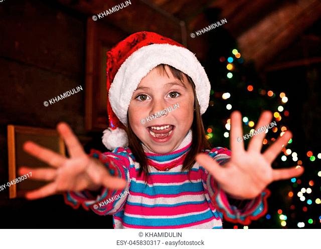 Happy child girl in a Christmas hat waiting for a miracle