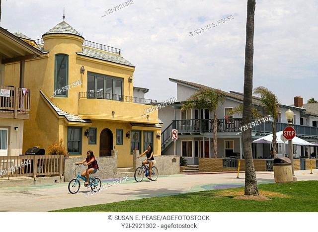 People bicycle past homes in Balboa Village, Newport Beach, Orange County, California, United States