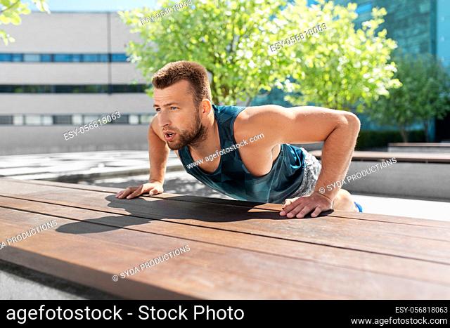 young man doing push ups on city street