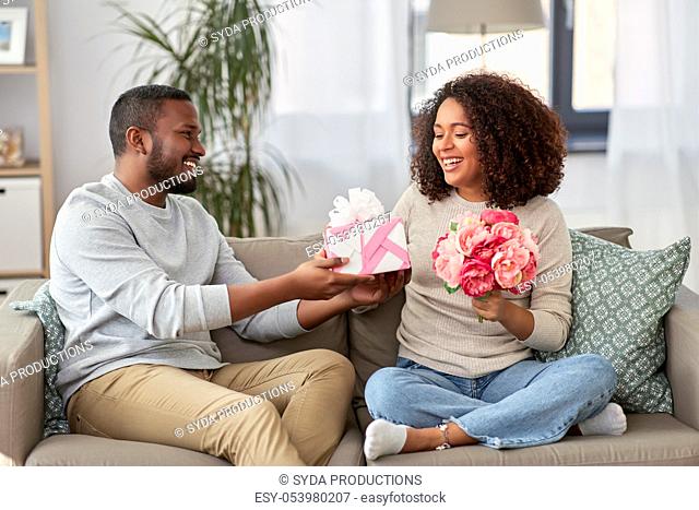 happy couple with flowers and gift at home