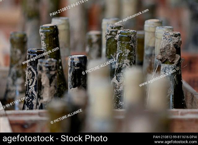 11 August 2021, Rhineland-Palatinate, Bad Neuenahr: Muddy wine bottles are sold as flood wine. On July 14 and 15, extremely heavy rain had triggered a flood...