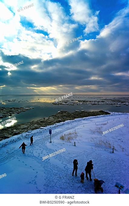 people at the snow-covered shore at harbour entrance with view at the shipping channel of Aussenweser, Germany, Lower Saxony, Landkreis Cuxhaven, Wremertief