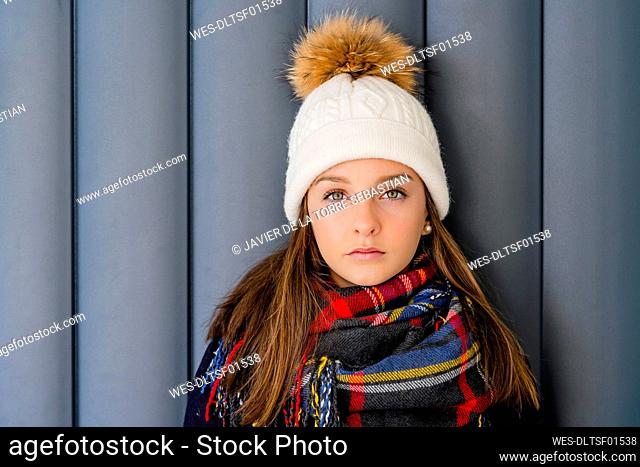 Close-up of serious teenage girl wearing warm clothing against wall at home