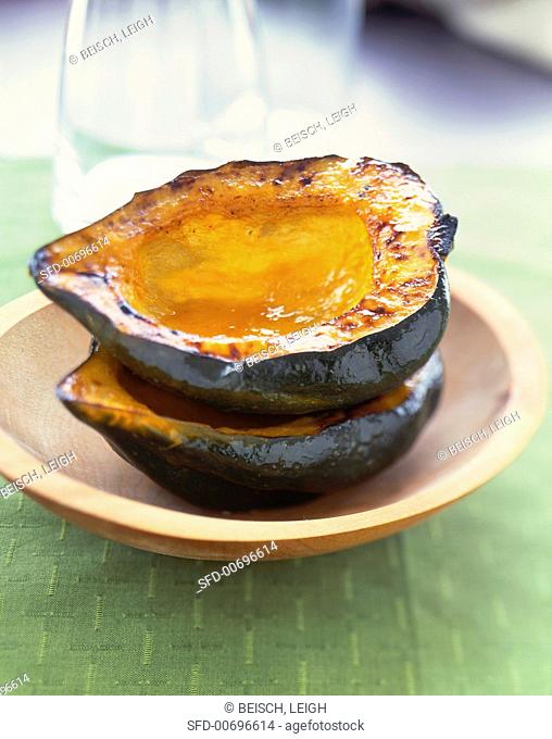 Two Halves of Roasted Acorn Squash Stacked in a Wooden Bowl