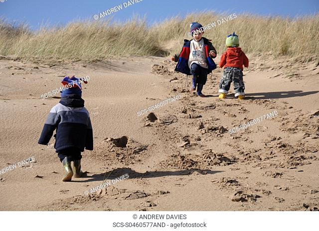 Three young boys playing in dunes, Broad Haven South, Stackpole, Pembrokeshire, Wales, UK, Europe