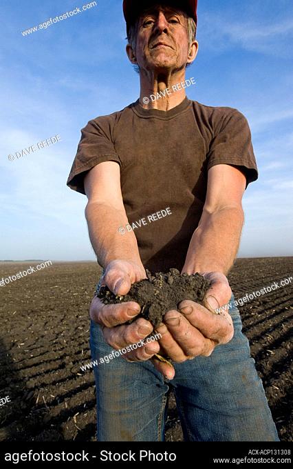 A man holds soil in a drought stricken field, Tiger Hills, Manitoba, Canada