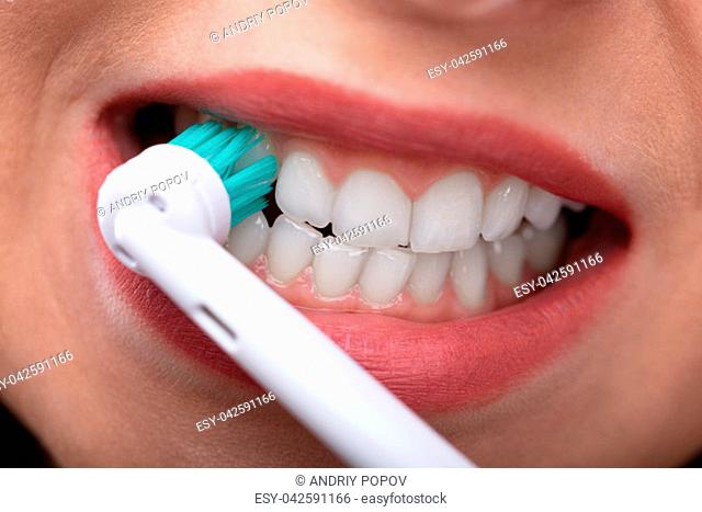 Close-up Of A Woman's Hand Brushing Teeth With Electric Toothbrush