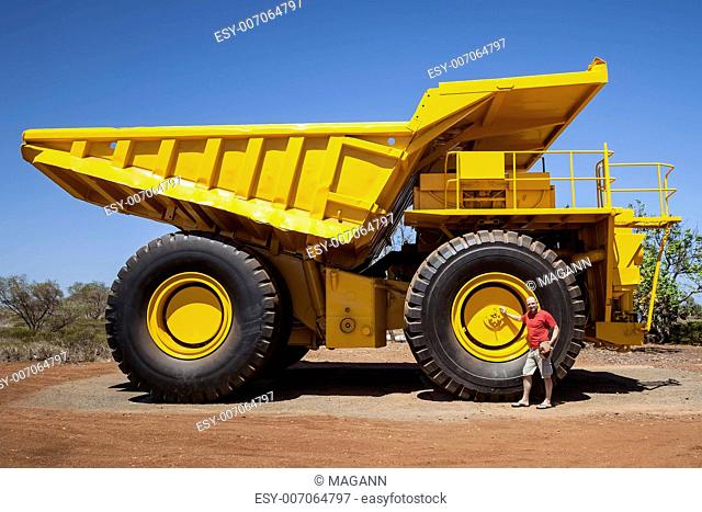 An image of a big yellow transporter and a man in front of a wheel