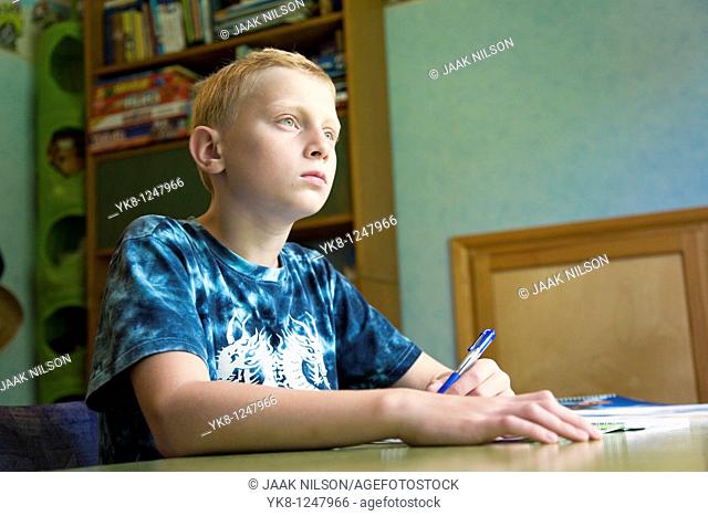 Serious Teenage Boy Sitting at Home Desk and Learning