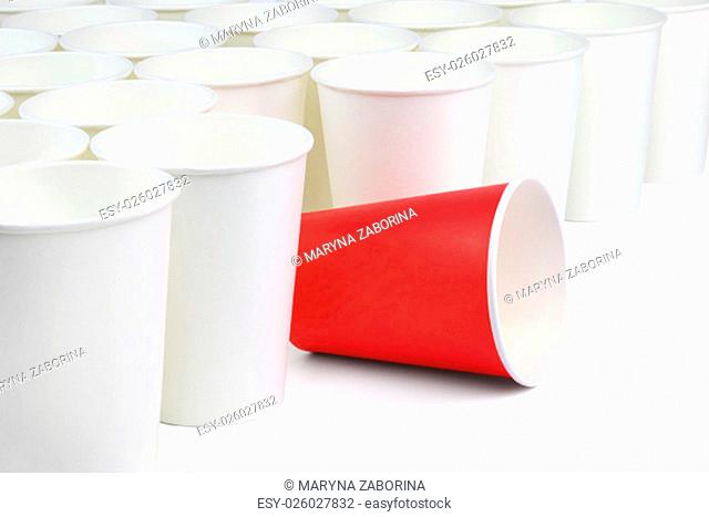 There is one red and many white empty paper cups isolated on white background. The white cups are on the diagonal of the image, the red cup is among them