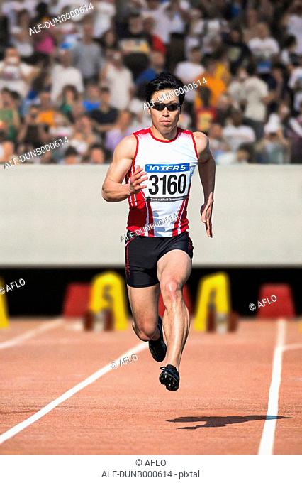 Japanese male sprinter running on track