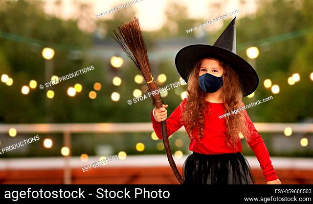 girl in black mask and halloween costume of witch