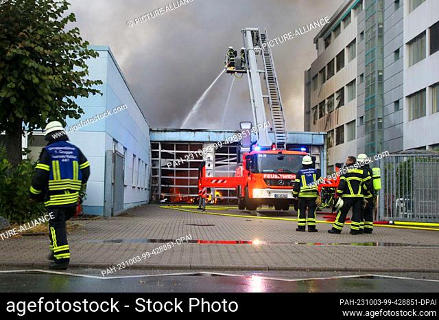 03 October 2023, Baden-Württemberg, Walldorf: Firefighters extinguish the fire in a laundry. A fire broke out at a laundry in the industrial area in Walldorf...