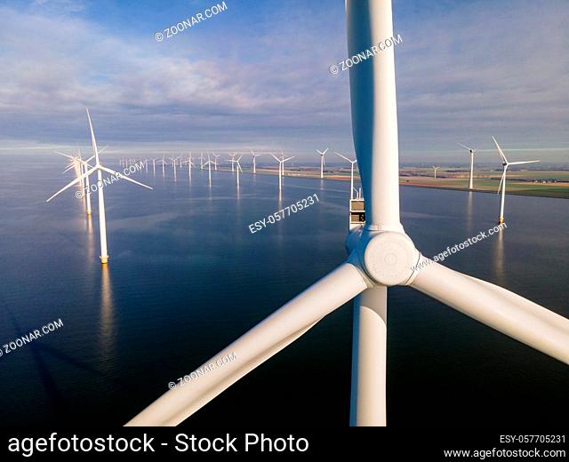 offshore windmill park with clouds and a blue sky, windmill park in the ocean drone aerial view with wind turbine Flevoland Netherlands Ijsselmeer