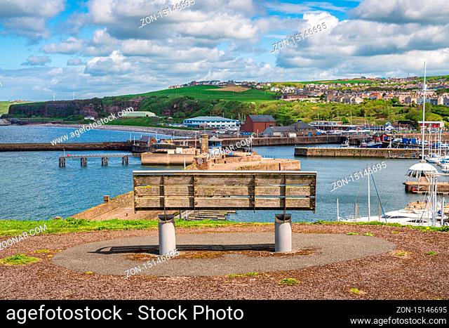 Whitehaven, Cumbria, England, UK - May 03, 2019: A bench with a view over the Whitehaven Marina and Bransty in the background