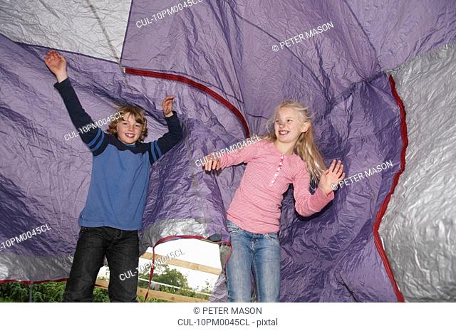Boy and girl playing under tent