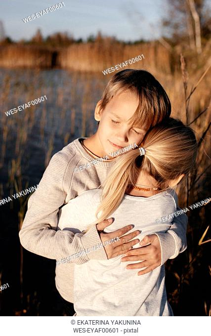 Portrait of boy hugging his little sister in autumnal nature