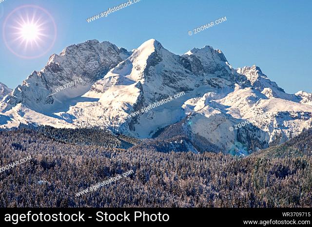 panoramic landscape in winter wirh mountain range and sun on sky